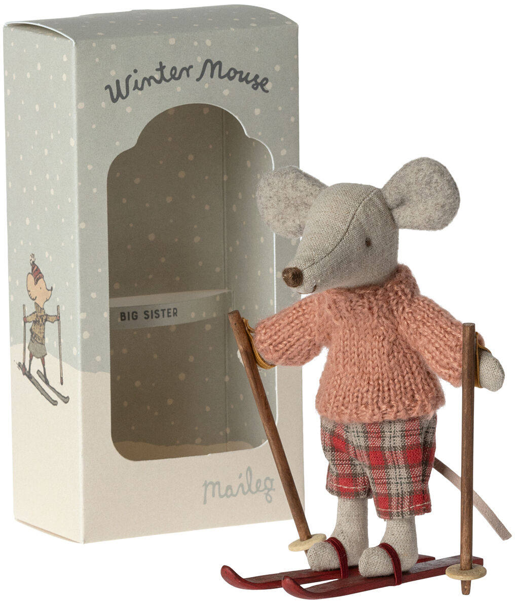 Eine Stoffmaus im Winteroutfit mit rosa Pullover und karierten Hosen auf Skiern, die neben einer Verpackung mit der Aufschrift 'Wintermaus' steht.