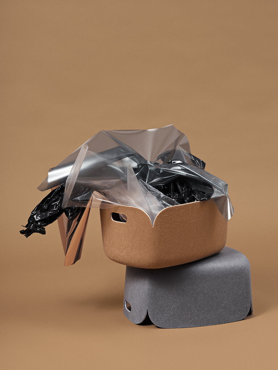 Ein moderner Aufbewahrungskorb in warmem Braun und Grau auf braunem Hintergrund, teilweise abgedeckt mit transparentem und schwarzem Kunststoff für eine stylische und funktionale Aufbewahrungslösung.