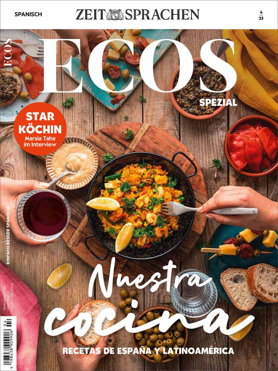Cover des Ecos Magazins 04/2023 Sonderausgabe mit dem Titel 'Nuestra cocina'. Auf dem Bild sind verschiedene spanische und lateinamerikanische Gerichte zu sehen, darunter ein Topf mit Essen in der Mitte, Weingläser und verschiedene Zutaten wie Paprika, Brot und Tomaten. Ein roter Stern auf der linken Seite hebt ein Interview mit María Taha hervor. Die Hintergrundfarben sind hauptsächlich braun und gelb mit Akzenten von rot, weiß, schwarz und grün.