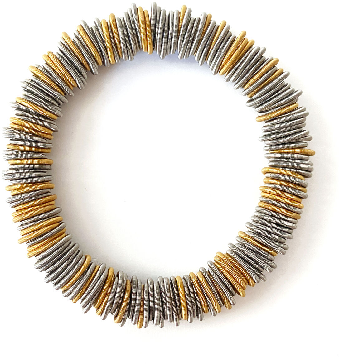Rundes Armband, bestehend aus abwechselnden goldenen und silbernen Metallscheiben, die auf ein elastisches Band gefädelt sind. Das Design ist modern und elegant.