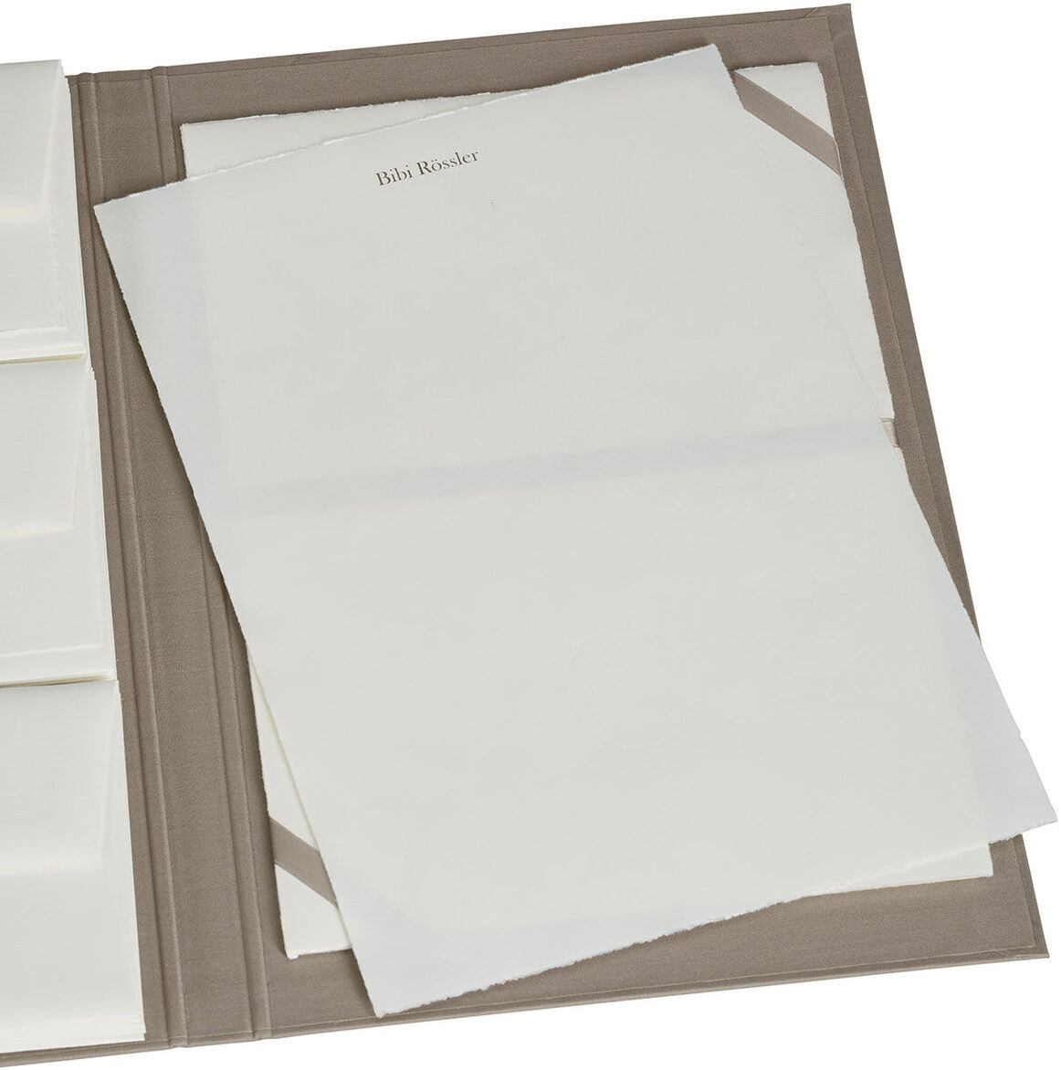 Eine elegante Briefpapiermappe mit edlem Büttenpapier. Die Mappe ist geöffnet und zeigt mehrere Fächer sowie lose Blätter aus hochwertigem Büttenpapier.