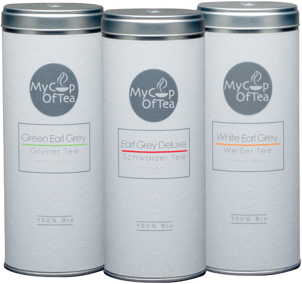 Drei zylindrische Weißblech-Dosen mit weißen Etiketten und den Aufschriften 'Green Earl Grey', 'Earl Grey Deluxe' und 'White Earl Grey'. Jede Dose hat das Logo 'My Cup of Tea' und die Beschriftung '100% Bio'.
