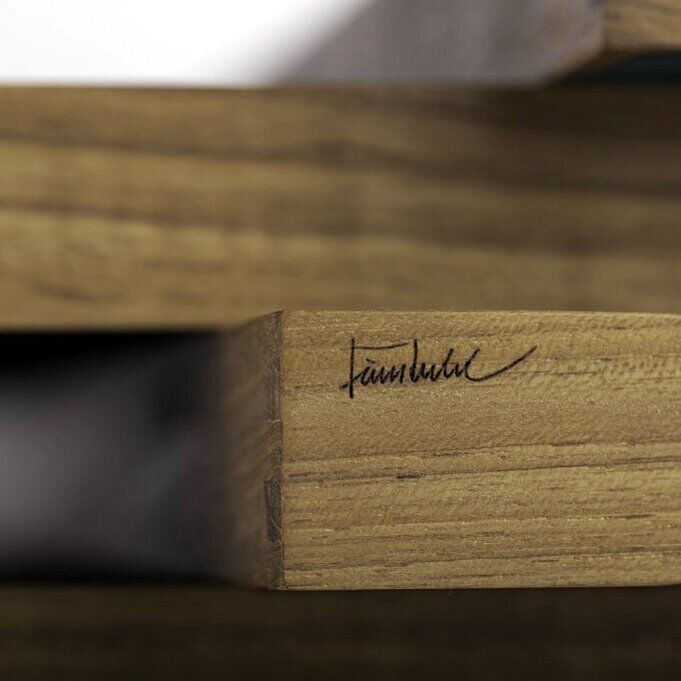 Detailaufnahme eines hochwertigen rechteckigen Tabletts aus Teakholz mit klar erkennbarer Eckverbindung und eingravierter Finn Juhl-Signatur. Im Bildhintergrund sind die unterschiedliche Oberflächenstruktur und feine Holzmaserung deutlich sichtbar. Die Kanten wirken präzise verarbeitet.