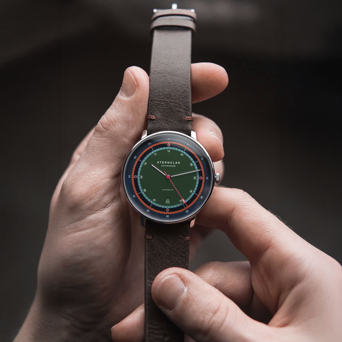 Die Sternglas ZEIT-Sonderedition »Hamburg Automatik« zeigt ein satiniertes Zifferblatt mit Farbverlauf in Grün, Blau und Orange, silbernes Edelstahlgehäuse und ein Vintage-Mokka-Lederarmband. Hochwertige Verarbeitung, klassisches und limitiertes Design. 42 mm Durchmesser.