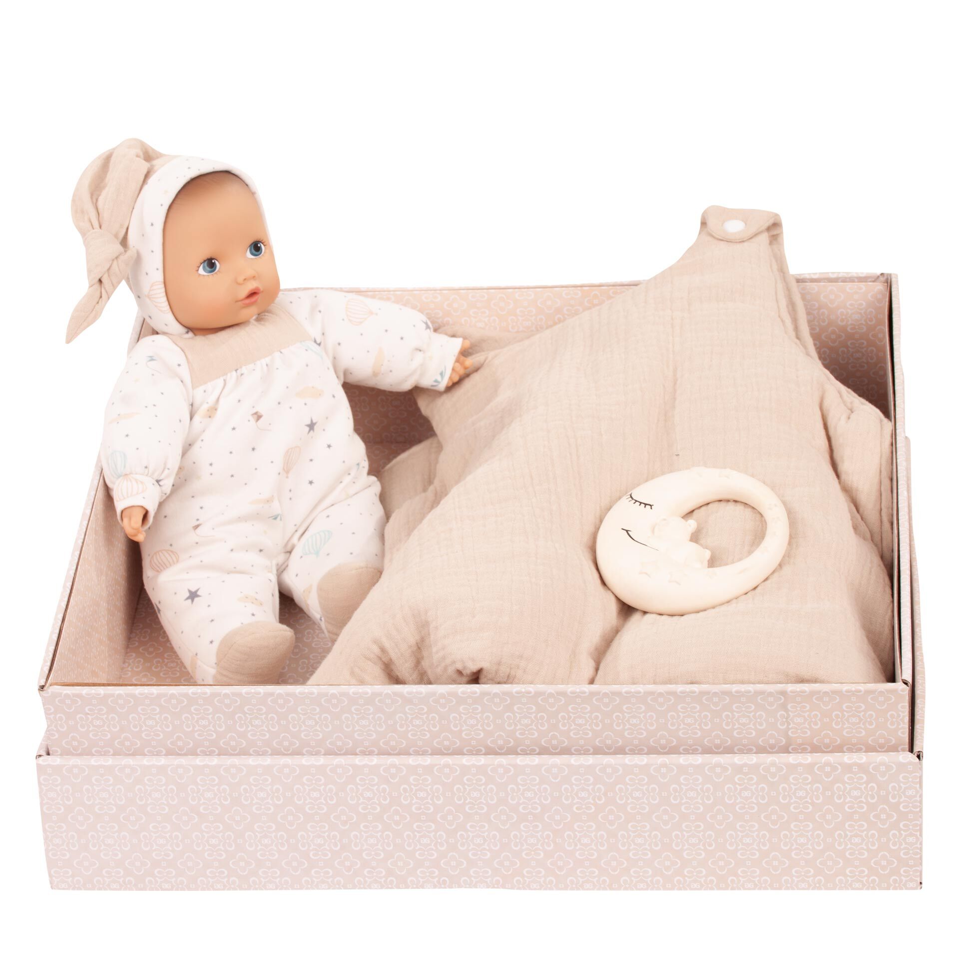 Eine Geschenkbox enthält eine beige-gemusterte Babypuppe im Schlafanzug, einen passenden Stoffschlafsack und einen runden Beißring mit Mondmotiv, alles in neutralen, hellen Farben gestaltet. Das Set eignet sich perfekt als Geschenk zur Geburt oder Taufe eines Neugeborenen.