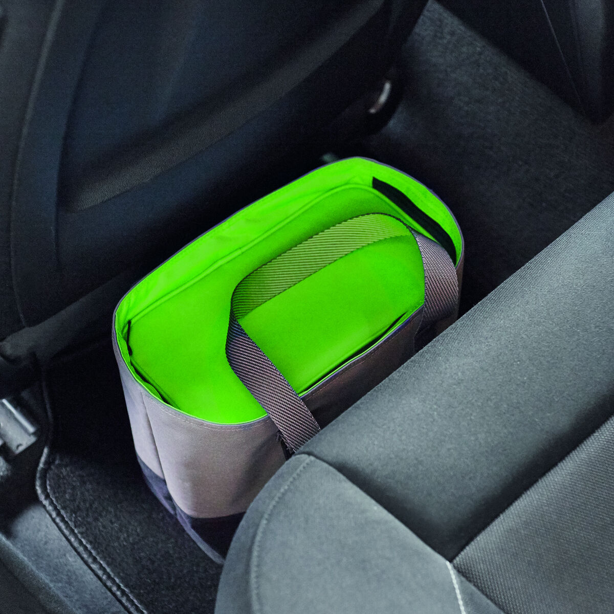 Eine grüne Lunch-Tasche, die im Fußraum eines Autos platziert ist, verwendet als Kühltasche zur Essensaufbewahrung unterwegs.