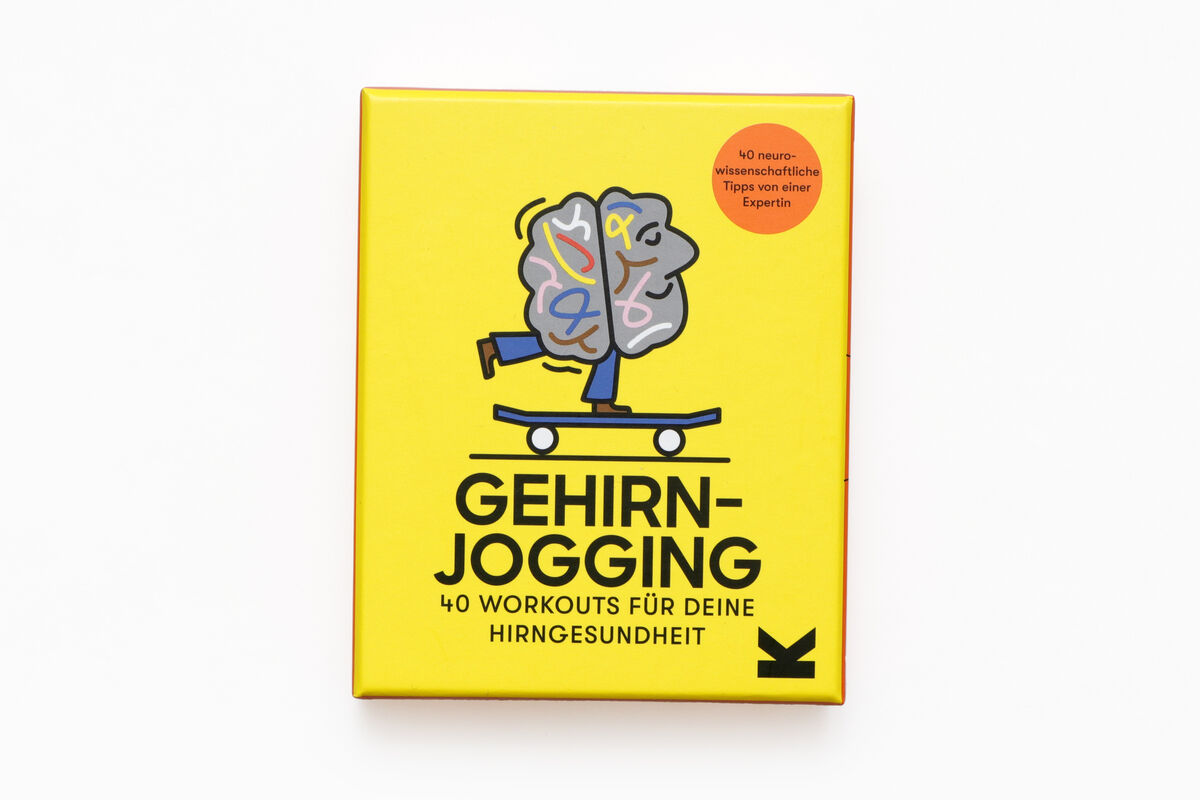 Eine gelbe Box mit der Aufschrift 'GEHIRNJOGGING' und einer Illustration eines Gehirns auf einem Skateboard. Der Text auf der Box besagt '40 Workouts für deine Hirngesundheit'.