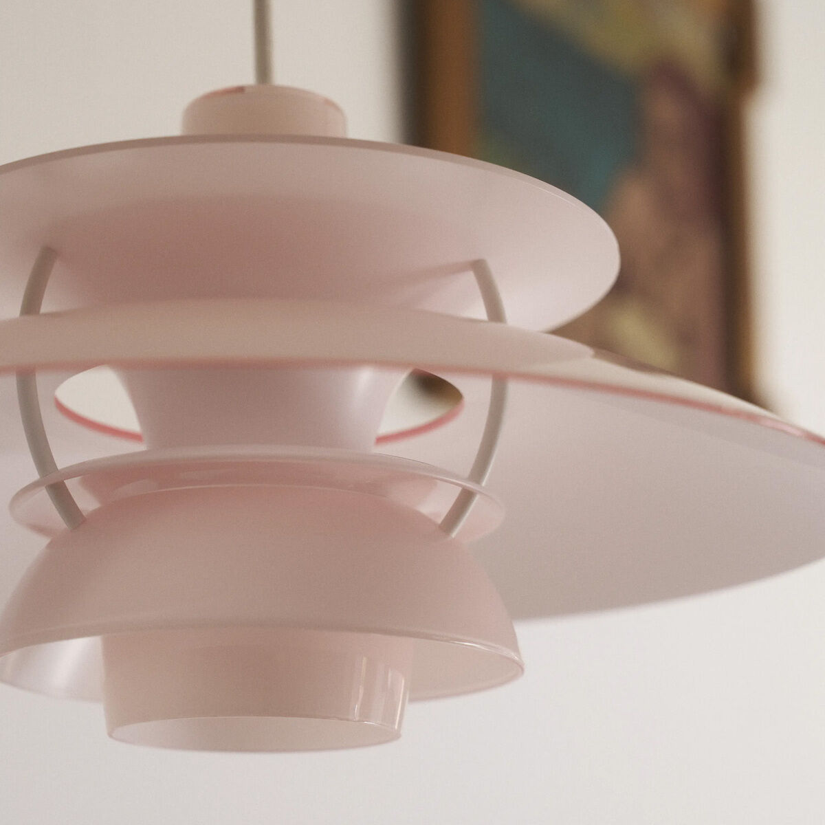 Detailansicht der Hängeleuchte »PH 5 320« von Louis Poulsen in zartem Weiß und Pale Rose. Die Leuchte besteht aus mehreren, geschwungenen Schirmen aus glänzendem Polymer und sorgt für blendfreies, nach unten gerichtetes Licht mit weicher Streuung im Raum.
