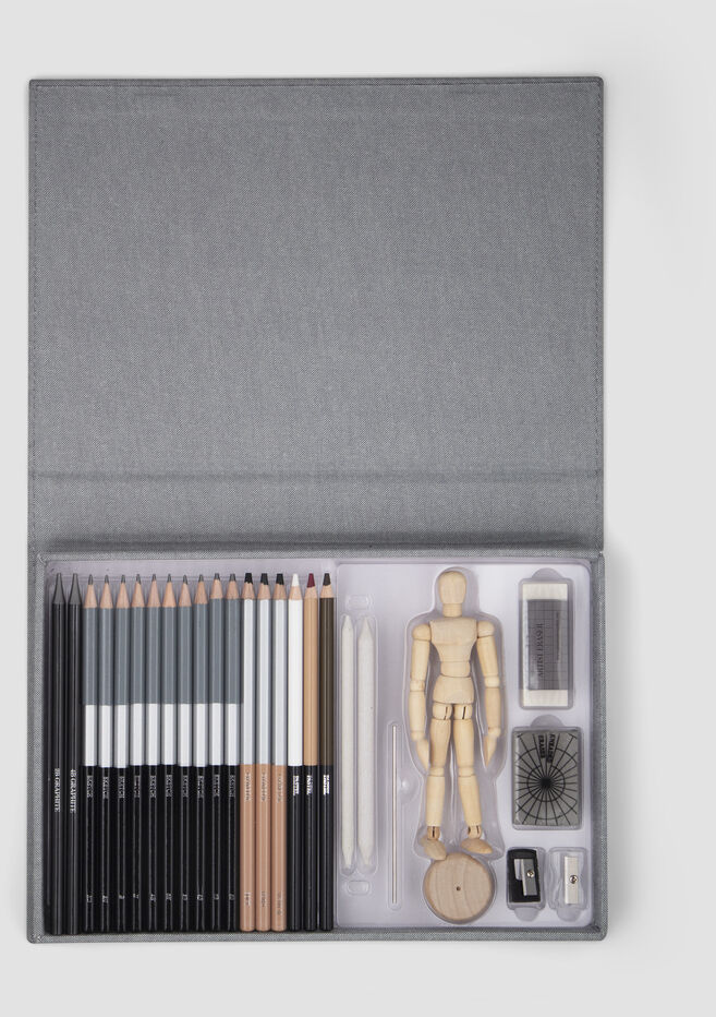 Ein Zeichenset, das Bleistifte, eine Holzmannequins, Radiergummi, Anspitzer und Kohle enthält, präsentiert in einer grauen Schachtel.