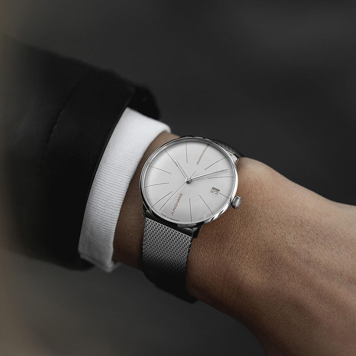 Eine elegante Armbanduhr der Sonderedition »Meister fein Kleine Automatic« von Junghans am Handgelenk eines Mannes. Die Uhr hat ein schlichtes Zifferblatt und ein Metallarmband. Das Design ist klassisch und minimalistisch.