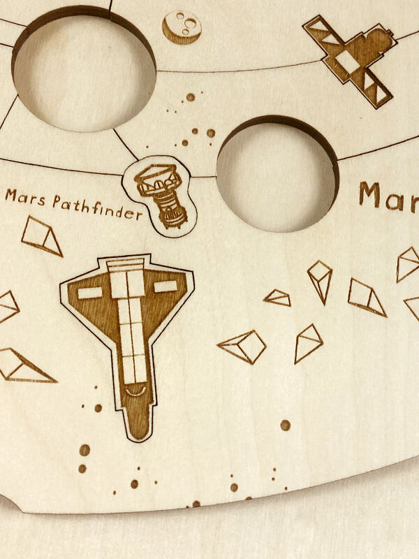 Holzpuzzle »Kosmos«, handgemachtes Puzzle aus hellem Holz, mit eingravierten Darstellungen von Planeten und Raumfahrzeugen wie dem Mars Pathfinder. Ideal für Kinder und Erwachsene, die an Astronomie und Wissenschaft interessiert sind.
