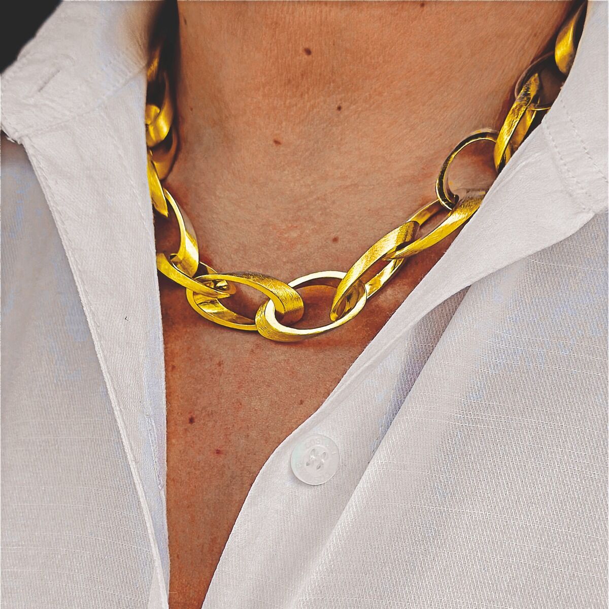 Großgliedriges Collier aus goldfarben feingoldplattiertem 925er Silber liegt auf dem Hals einer Person, die ein weißes Hemd trägt. Die Kette wirkt elegant und edel, hebt sich glänzend vom Stoff ab und betont den Ausschnitt.