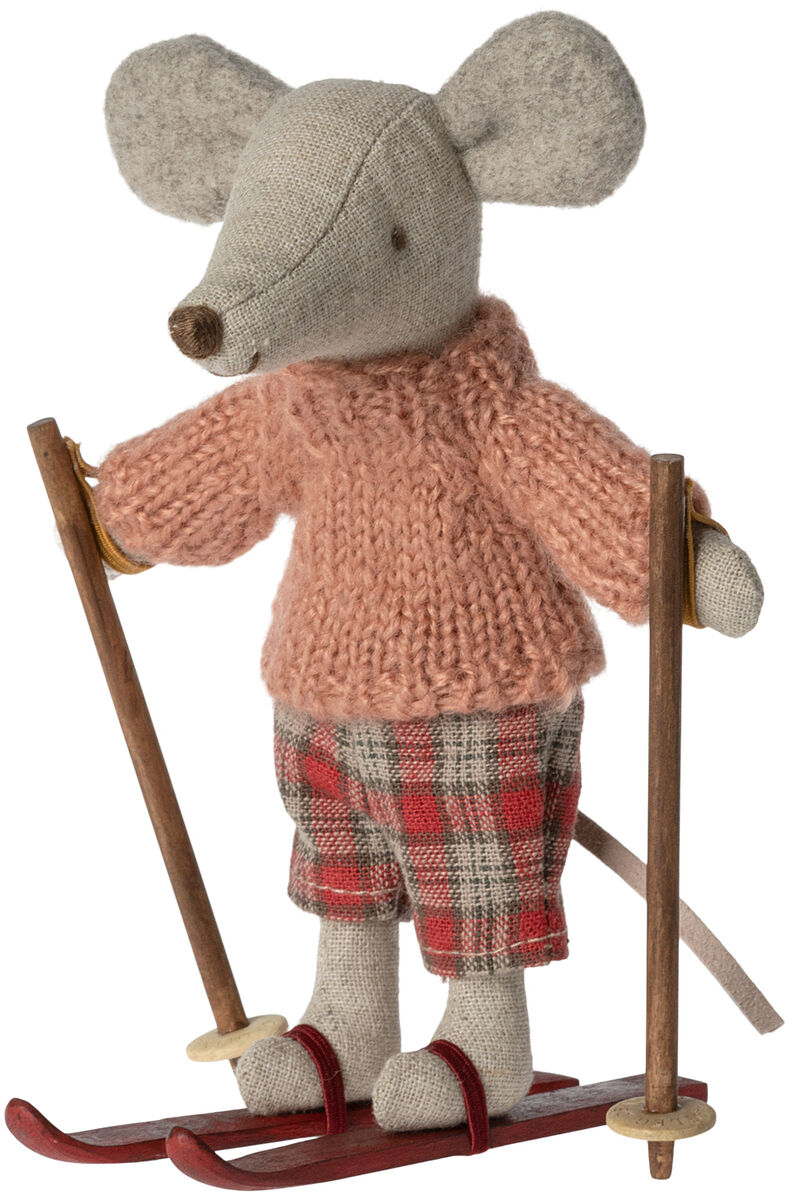 Handgemachte Stoffmaus in rosa Strickpullover und karierten Hosen, stehend auf roten Skiern mit Skistöcken in den Pfoten.