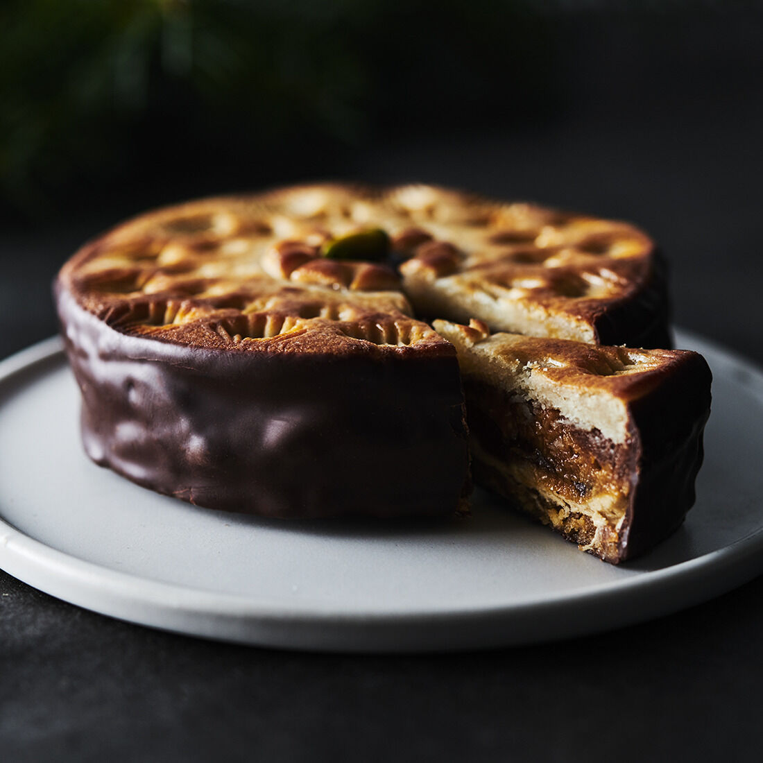 Eine reichhaltige, schokoladenüberzogene Sawade-Torte in einer Geschenkschachtel, die kunstvoll verziert und auf einem Teller angerichtet ist.