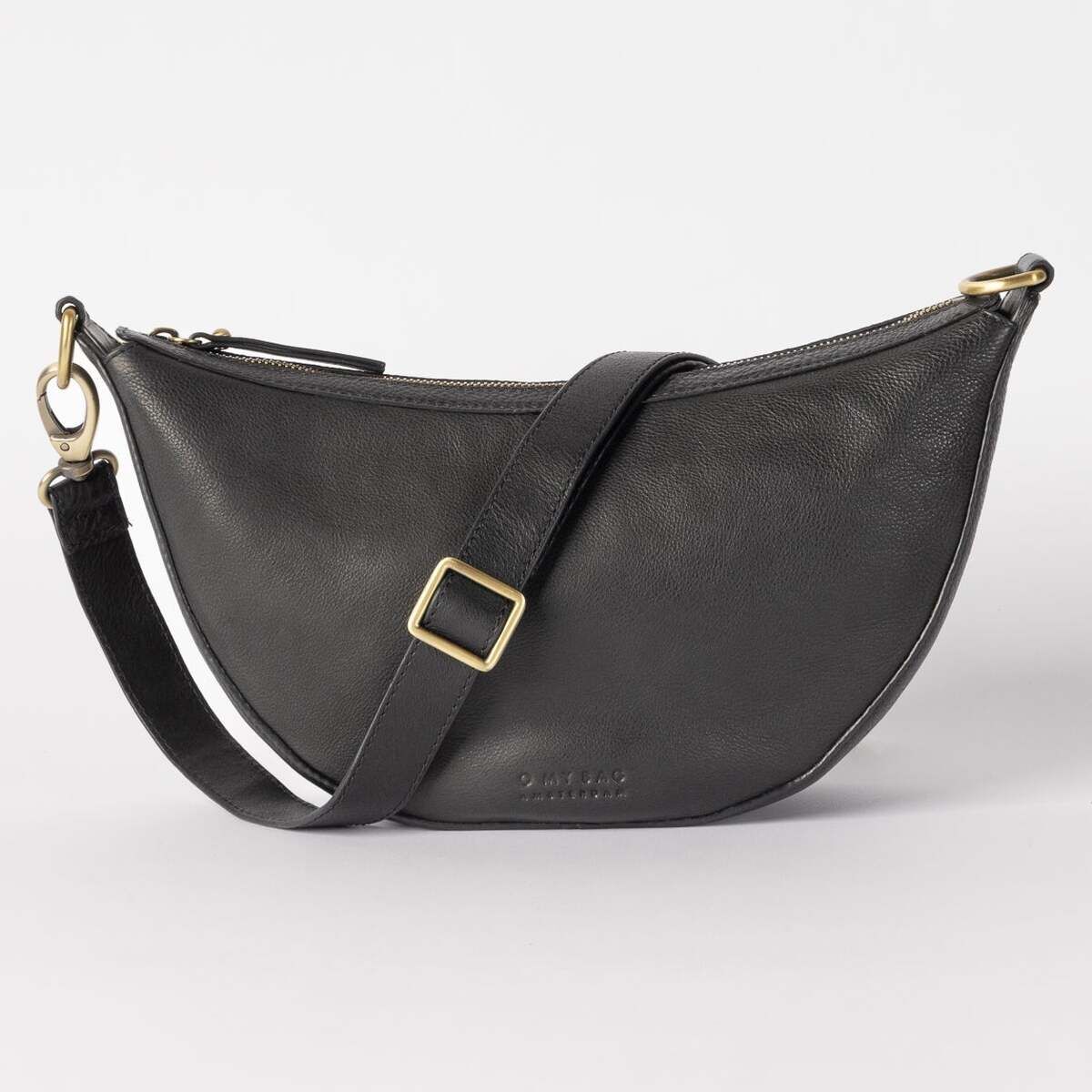 Schwarze Handtasche aus Leder in Halbmondform mit verstellbarem Schulterriemen und goldfarbener Metallschnalle, auf hellem Hintergrund fotografiert.