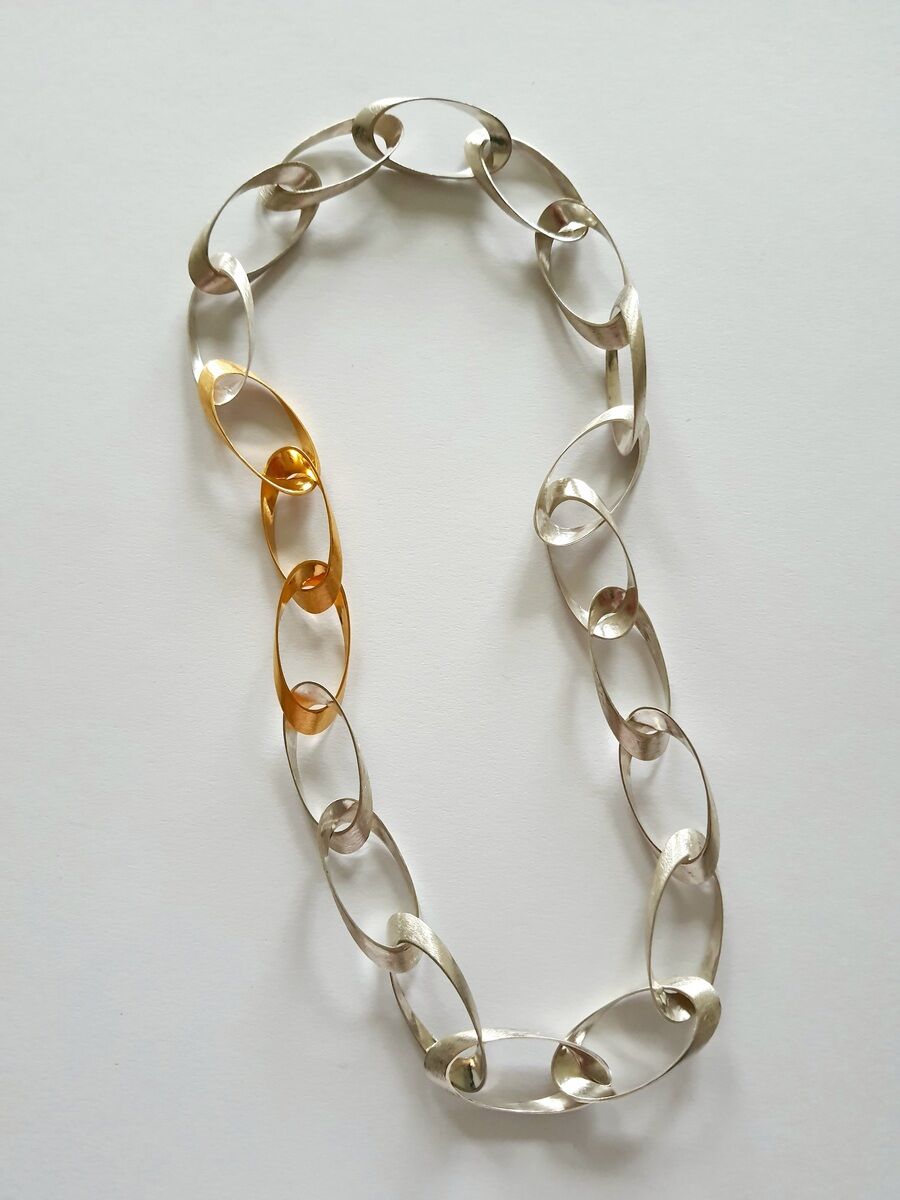 Eine Halskette aus einer Kombination von Silber- und Goldelementen, bestehend aus ovalen Gliedern. Die Kette hat ein modernes und elegantes Design.