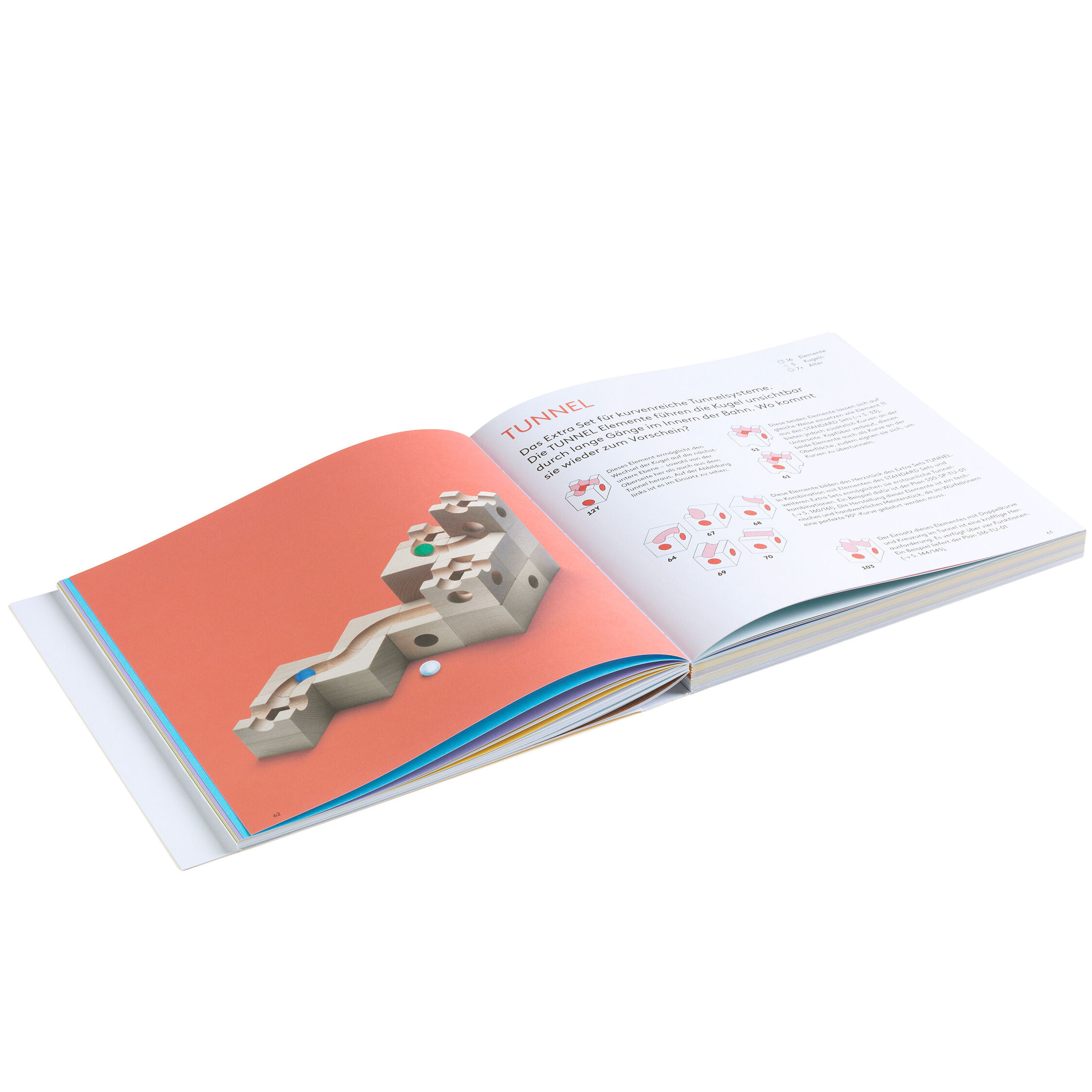 Offen liegendes Buch zur Kugelbahn »CUBORO - DAS BUCH« von Cuboro mit illustrierten Kugelbahn-Bauanleitungen und erklärenden Texten. Links eine 3D-Abbildung eines Kugelbahnaufbaus auf orangefarbenem Hintergrund, rechts detaillierte Bauanweisungen auf weißem Grund.