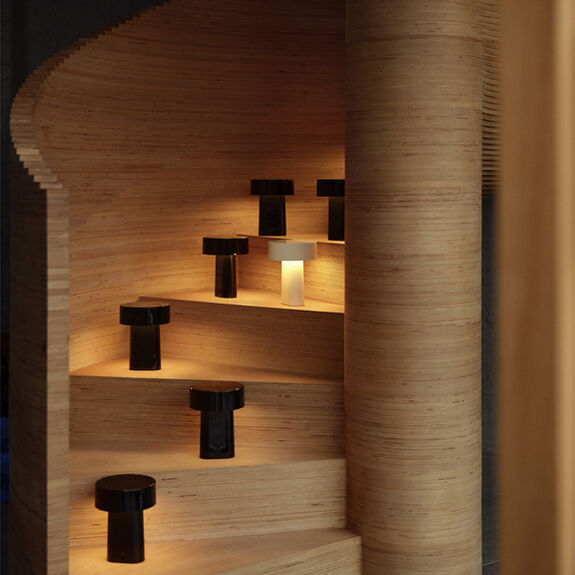 Mehrere tragbare Lampen vom Modell Oblong leuchten auf den Stufen einer geschwungenen Holztreppe, schaffen eine warme und moderne Atmosphäre.