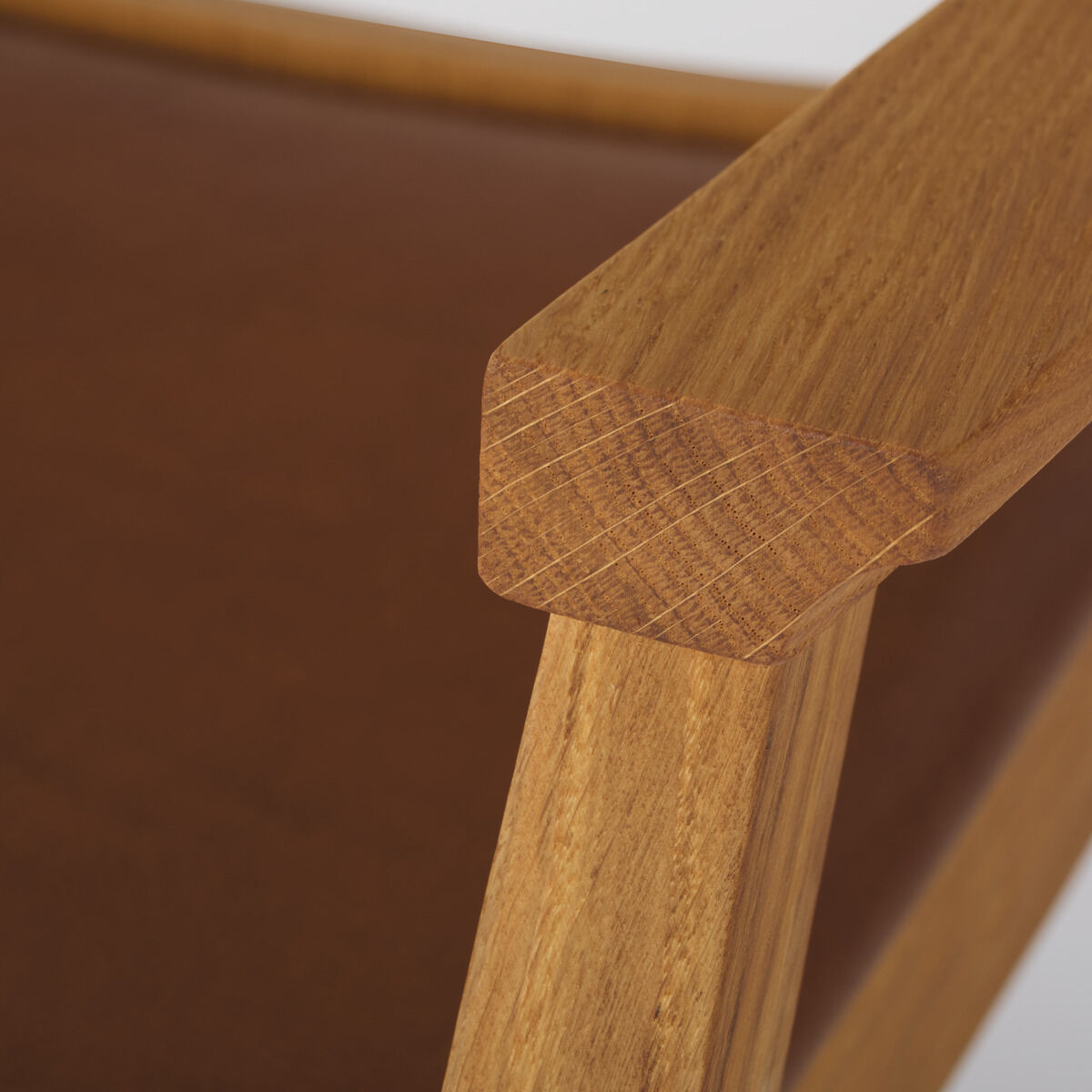 Ein Armlehnstuhl aus Holz mit einem minimalistischen Design. Der Stuhl zeigt eine feine Verarbeitung und glatte Oberflächen mit einem Fokus auf Komfort und Ästhetik.