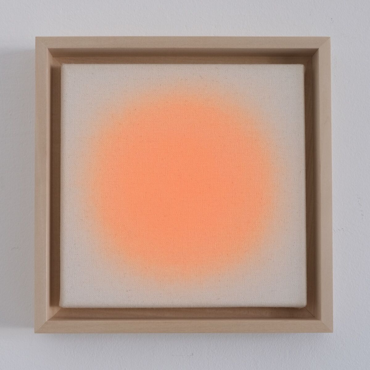 Quadratisches Kunstwerk mit einem subtilen, orangefarbenen Farbverlauf in der Mitte auf hellem Hintergrund, gerahmt in einem naturbelassenen Holzrahmen und an einer weißen Wand hängend.