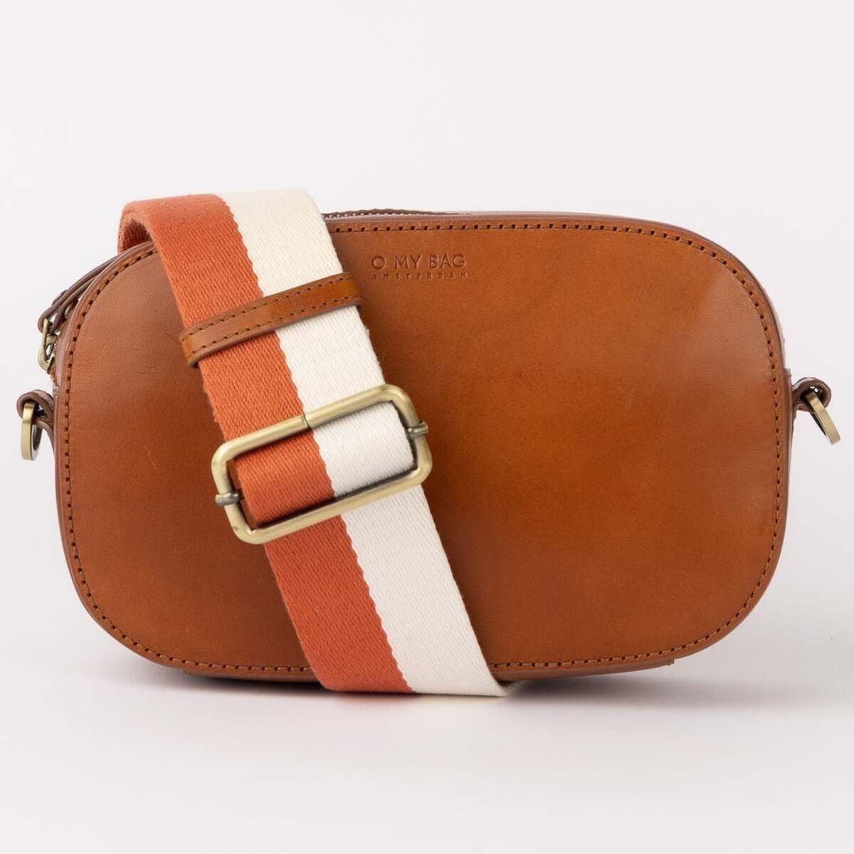 Kleine Leder-Umhängetasche 'Maya' mit verstellbarem Gurt in Orange und Weiß, aus Stoff. Das Leder ist cognacfarben. Die Beschläge in antiken Messing. Das Design ist modern und minimalistisch mit goldfarbener Schnalle am Gurt.