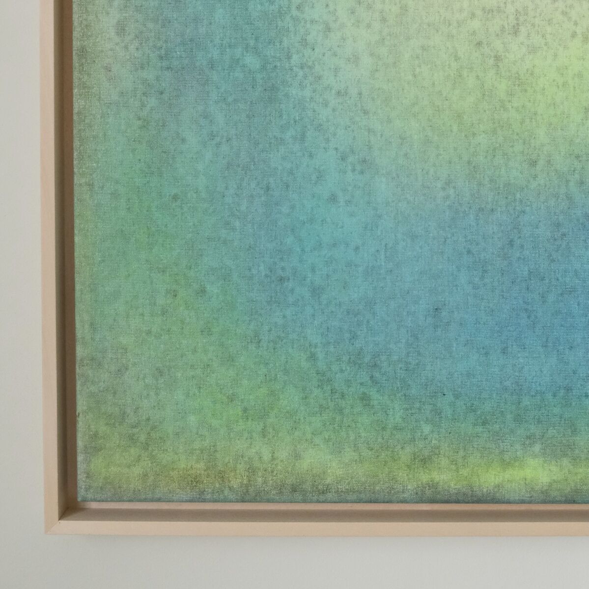 Abstraktes Kunstwerk in Blau-, Grün- und Gelbtönen, eingerahmt in einem schmalen Holzrahmen. Das Bild hat eine weiche Übergangsstruktur und erinnert an ein Aquarell.