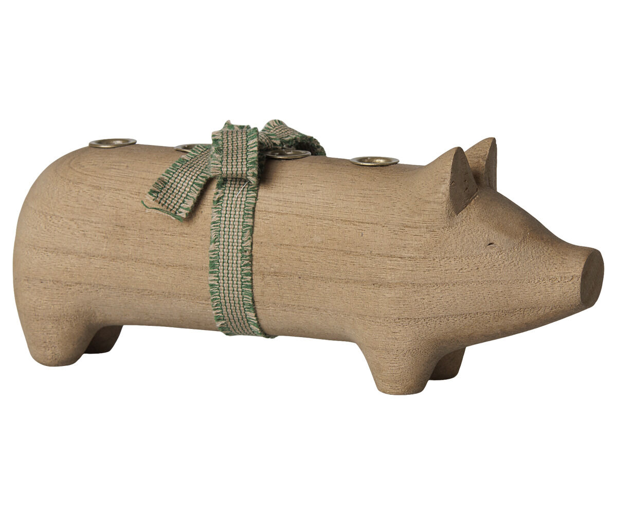 Mittelgroßer Kerzenhalter in Schweineform aus naturfarbenem Holz von Maileg. Auf dem Rücken befindet sich eine grüne Stoffschleife und es sind Kerzenhalterungen eingelassen. Das Schwein steht auf vier Beinen, hat Ohren und einen angedeuteten Rüssel.