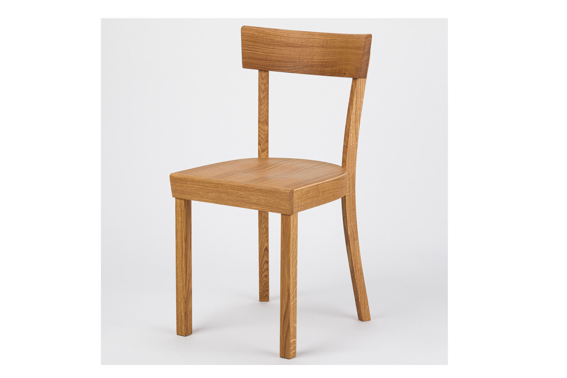 Ein schlichter Küchenstuhl aus geölter Eiche mit gerader Rückenlehne und klaren Linien steht vor neutralem, hellem Hintergrund. Der Stuhl kombiniert klassisches deutsches Design mit moderner Handwerkskunst.