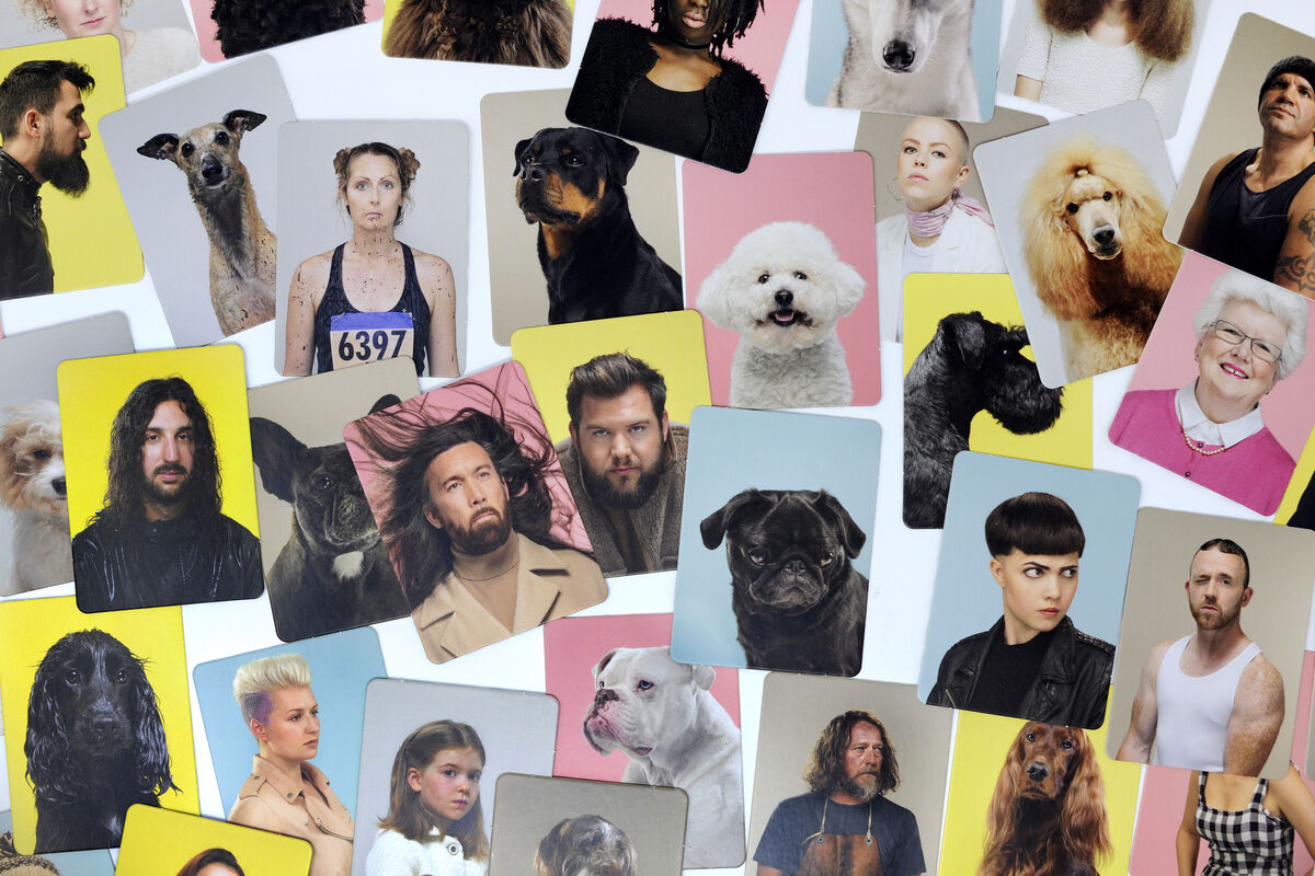 Verschiedene Karten eines Memo-Spiels, das Menschen und ihre Hunde zeigt. Die Karten haben bunte Hintergrundfarben wie Gelb, Rosa, Blau und Grau.