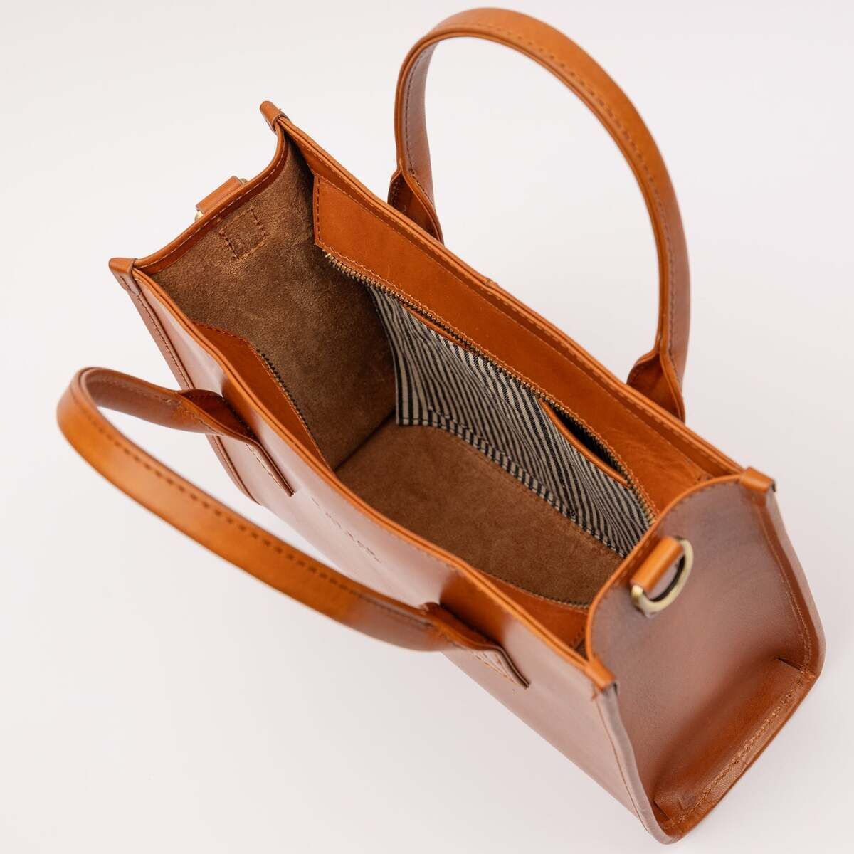 Offene mittelgroße Ledertasche in Cognacbraun mit zwei Henkeln und gestreiftem Innenfutter, stilvoll und funktional, ideal für Damen und verschiedene Anlässe.