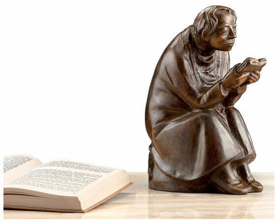 Eine bronzene Skulptur von Ernst Barlach aus dem Jahr 1936, die einen sitzenden Buchleser zeigt. Die Figur hält ein Buch in der Hand und hat detaillierte Gesichtszüge und Kleidung. Die Skulptur steht auf einer Plattform neben einem offenen Buch.