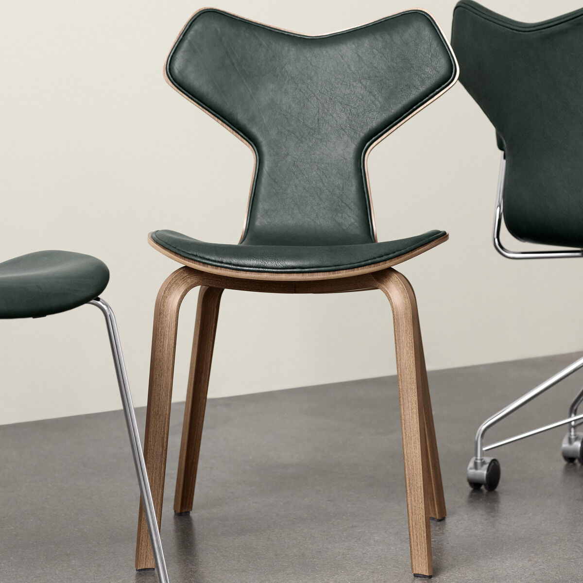 Ein stilvoller Stuhl aus der Pure Collection mit grünem Lederbezug und einem Gestell aus Walnussholz. Geeignet für modernes Design und minimalistisches Interieur.