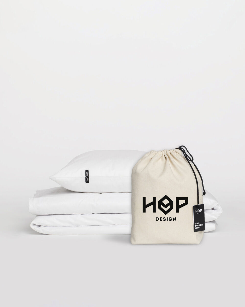 Ein Set Bettwäsche »Pure« von Hop Design, bestehend aus einem Kissen und einer Bettdecke in weißer Farbe, mit einem beigefarbenen Aufbewahrungsbeutel. Perfekt für ein modernes und schlichtes Schlafzimmer-Design.