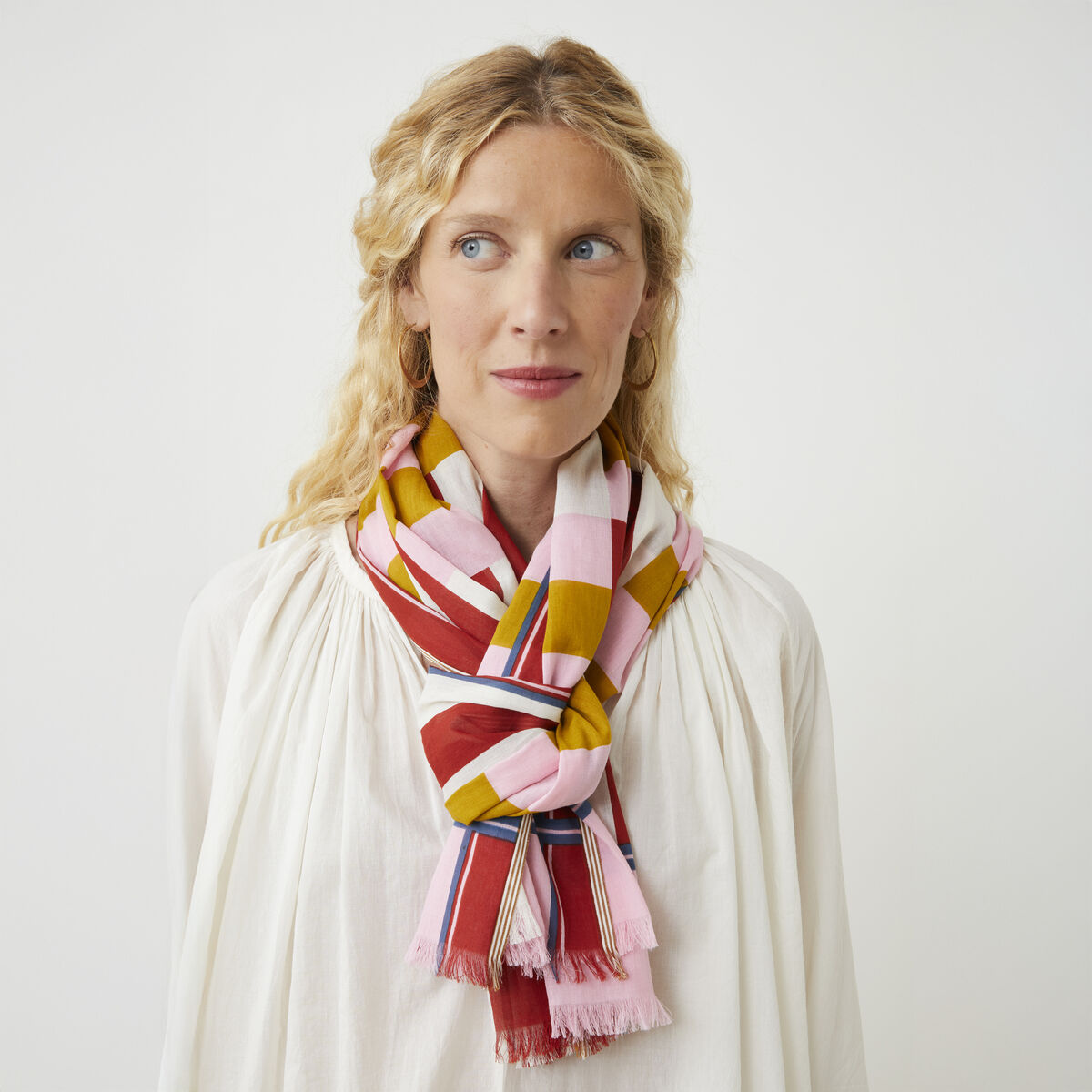 Baumwollschal »No. 771« von MOISMONT, 100% Baumwolle, fein gewebter Stoff. Das Design zeigt ein klar strukturiertes Muster aus farbigen Blockstreifen in Beige, Rot, Blau und Grün. Schal liegt locker gefaltet auf hellem Untergrund, Maße ca. 70x180 cm.