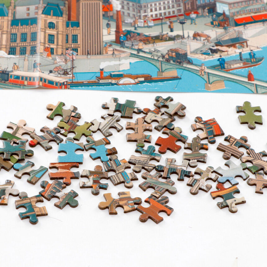 Ein Sherlock Holmes Welt Puzzle, das verstreute Puzzleteile auf einem Tisch zeigt, mit einem teilweise zusammengesetzten Bild von einer Stadt im Hintergrund.