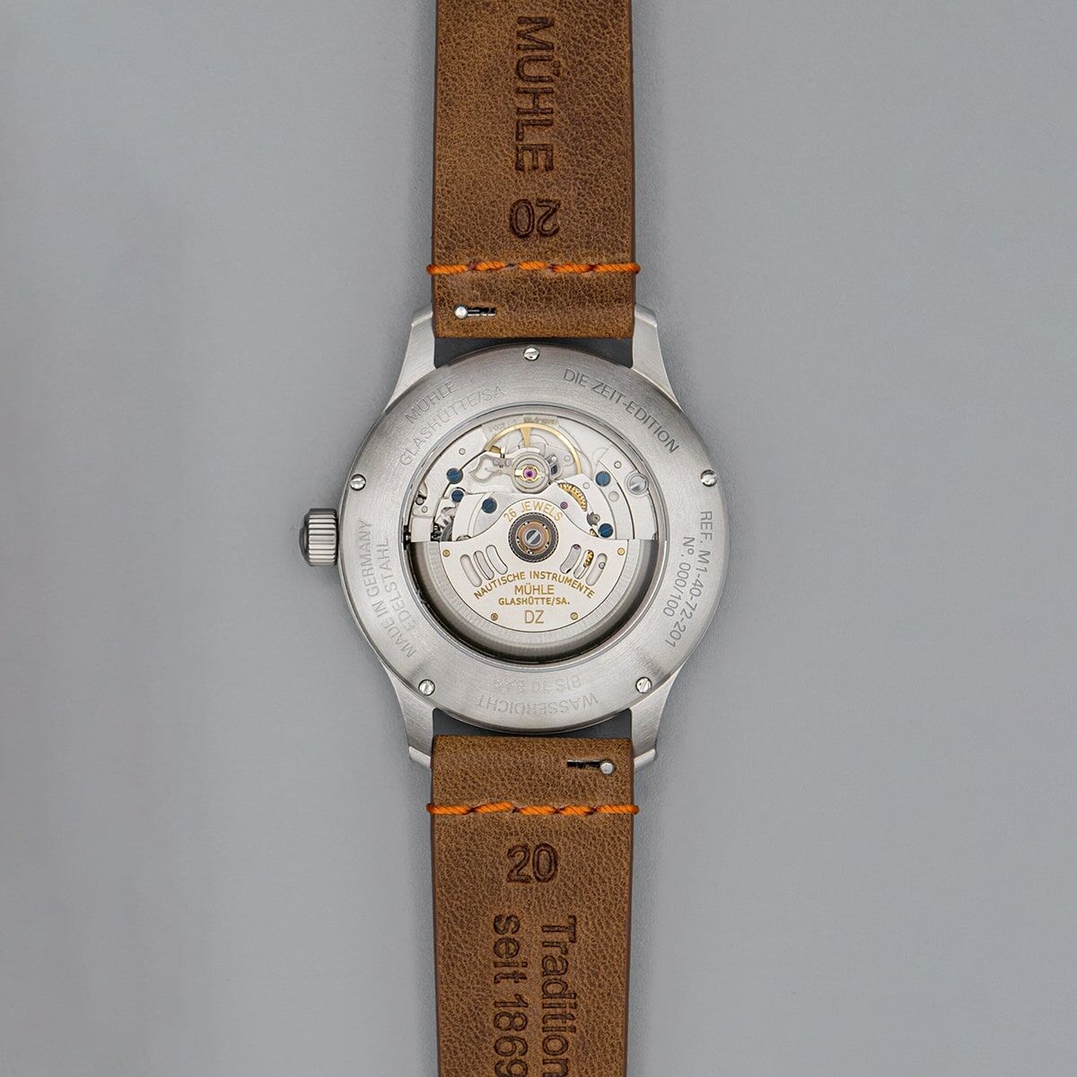 Rückseite einer eleganten Armbanduhr der ZEIT-Sonderedition »Panova Grau« von Mühle Glashütte mit sichtbarem mechanischem Uhrwerk und braunem Lederarmband.