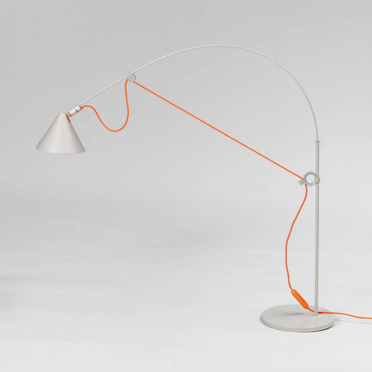 Eine moderne Tischlampe des Modells »AYNO« Silk mit einem minimalistischen Design. Die Lampe ist weiß und grau, mit einem langen, geschwungenen Arm und einem orangefarbenen Kabel. Sie steht auf einem runden Sockel und hat einen konischen Lampenschirm.