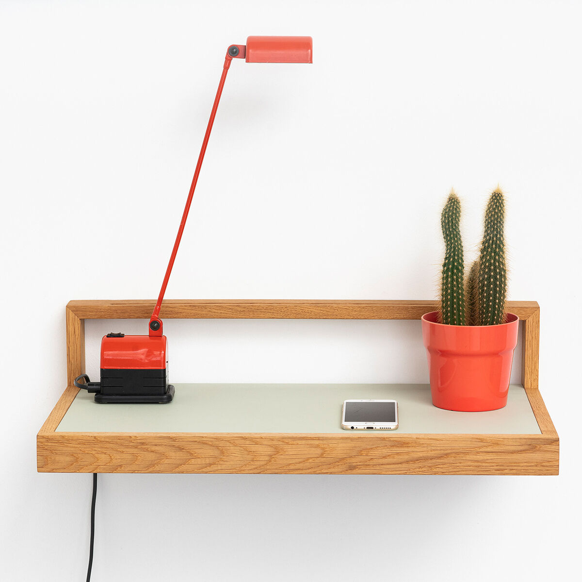 Ablagebord »buck« pistazie: minimalistisches Wandregal mit Holzrahmen, einer roten Lampe, einem Kaktus im roten Blumentopf und einem Smartphone auf der Ablagefläche.