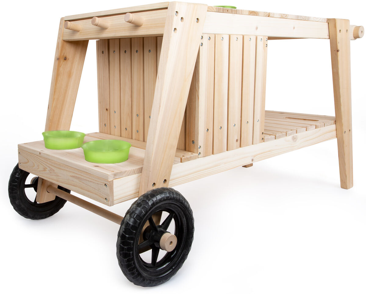 Ein Bild einer Matschküche für Kinder aus hellem Holz mit zwei grünen Schüsseln und schwarzen Rädern. Die Küche hat eine rustikale, natürliche Optik und ist für Outdoor-Aktivitäten geeignet.