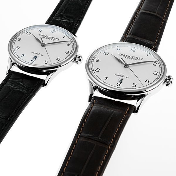 Zwei Edelstahl-Uhren der Edition »ZEIT 1« mit weißem Ziffernblatt, schwarzen Lederarmbändern und minimalistischen, schwarzen Ziffern auf weißem Hintergrund.