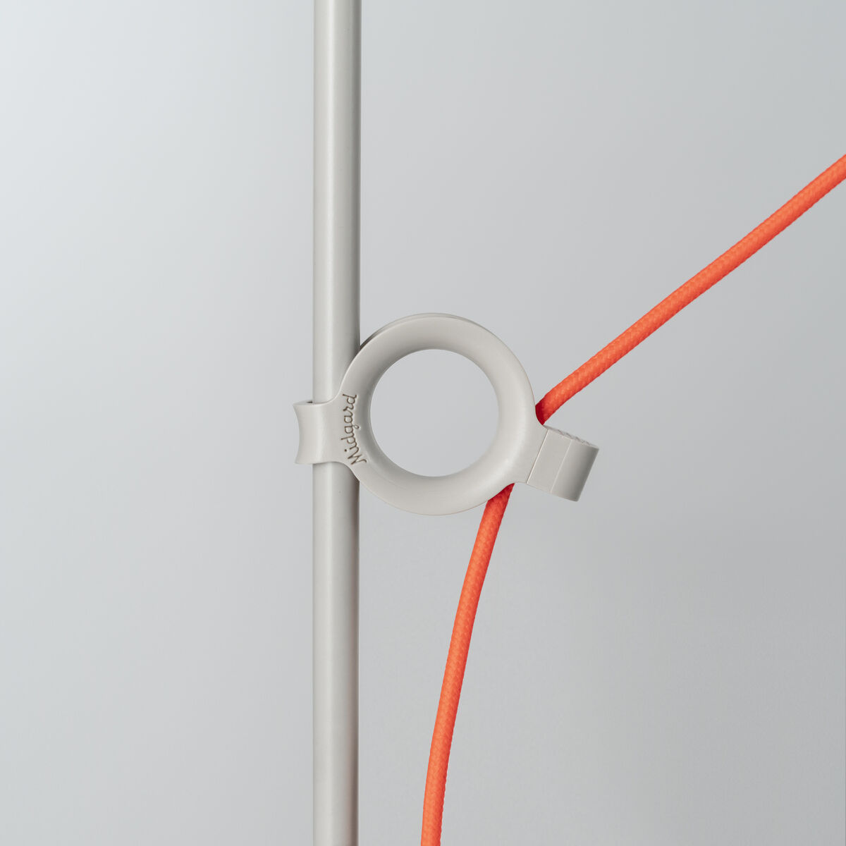 Nahaufnahme der Tischlampe »AYNO« Silk mit einem grauen Lampenkörper und einem orangefarbenen Stromkabel. Modernes, minimalistisches Design.