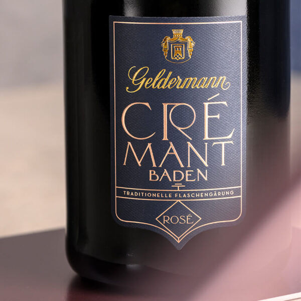 Flasche Crémant Spezialitäten mit Neoprenmanschette von Geldermann aus Baden. Der Etikettentext hebt die traditionelle Flaschengärung und die Eleganz des Produkts hervor.