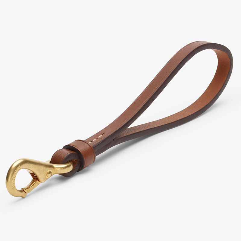 Naturbrauner Schlüsselanhänger aus pflanzlich gegerbtem Rindleder in Schlaufenform mit feinen weißen Nähten und massivem, goldfarbenem Karabinerhaken. Die polierten Kanten und dezente Prägungen verleihen dem Anhänger einen hochwertigen und zeitlosen Look.