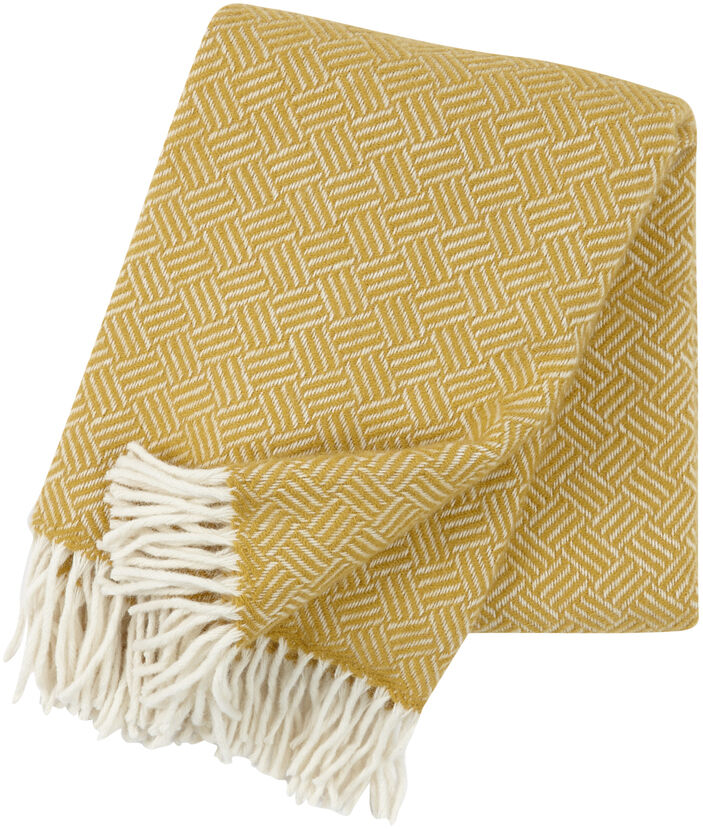 Eine gelbe Decke mit weißem geometrischem Muster und weißen Fransen auf einer Seite, zusammengerollt und auf einer weißen Fläche dargestellt.