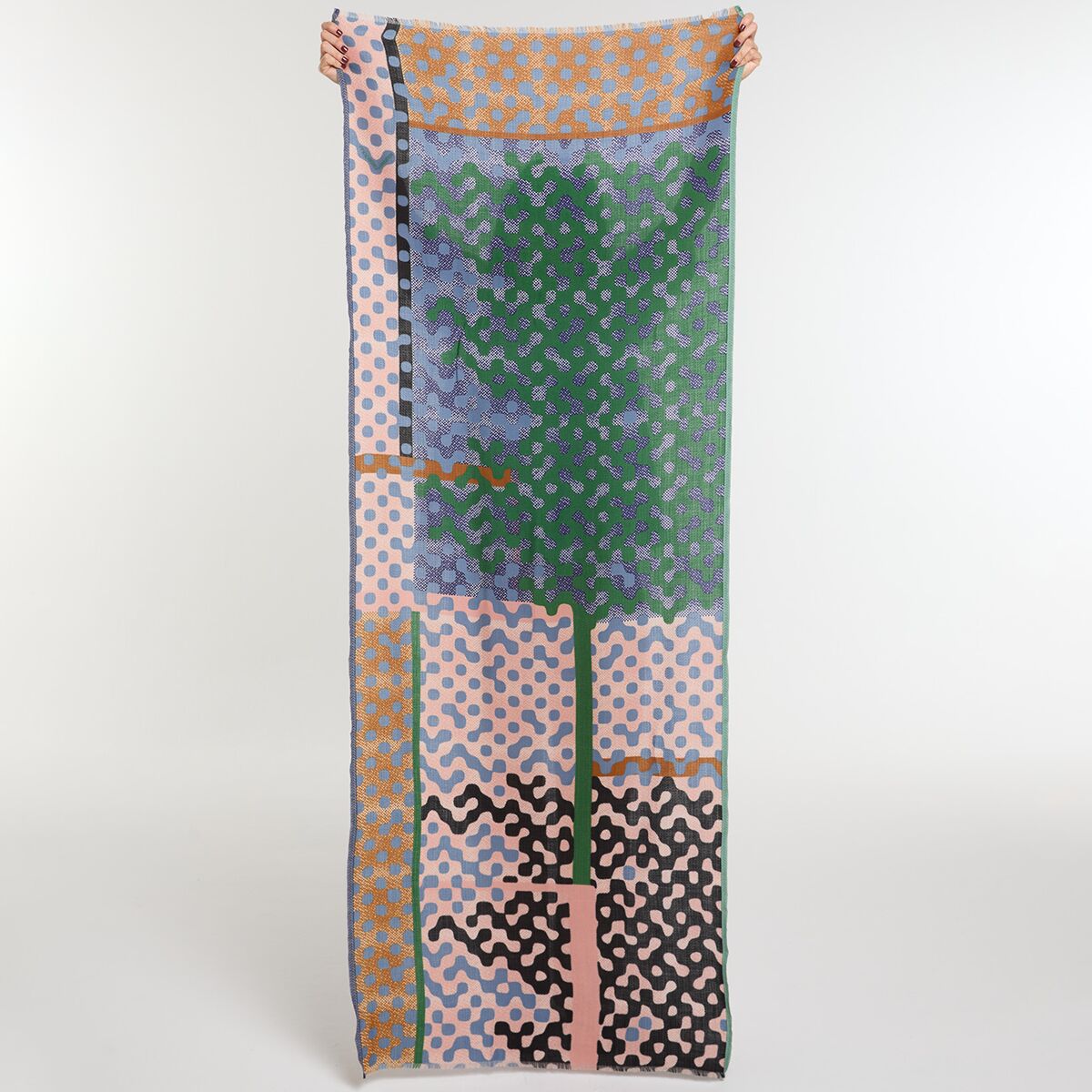 Langer Wollschal mit modernem, gemustertem Design in Grün, Braun, Blau, Rosa, Orange und Schwarz, ausgebreitet vor hellem Hintergrund. Der Schal zeigt verschiedene Bereiche mit unterschiedlichen geometrischen Mustern und eignet sich für Damen und Herren als modisches Accessoire für kühle Tage.