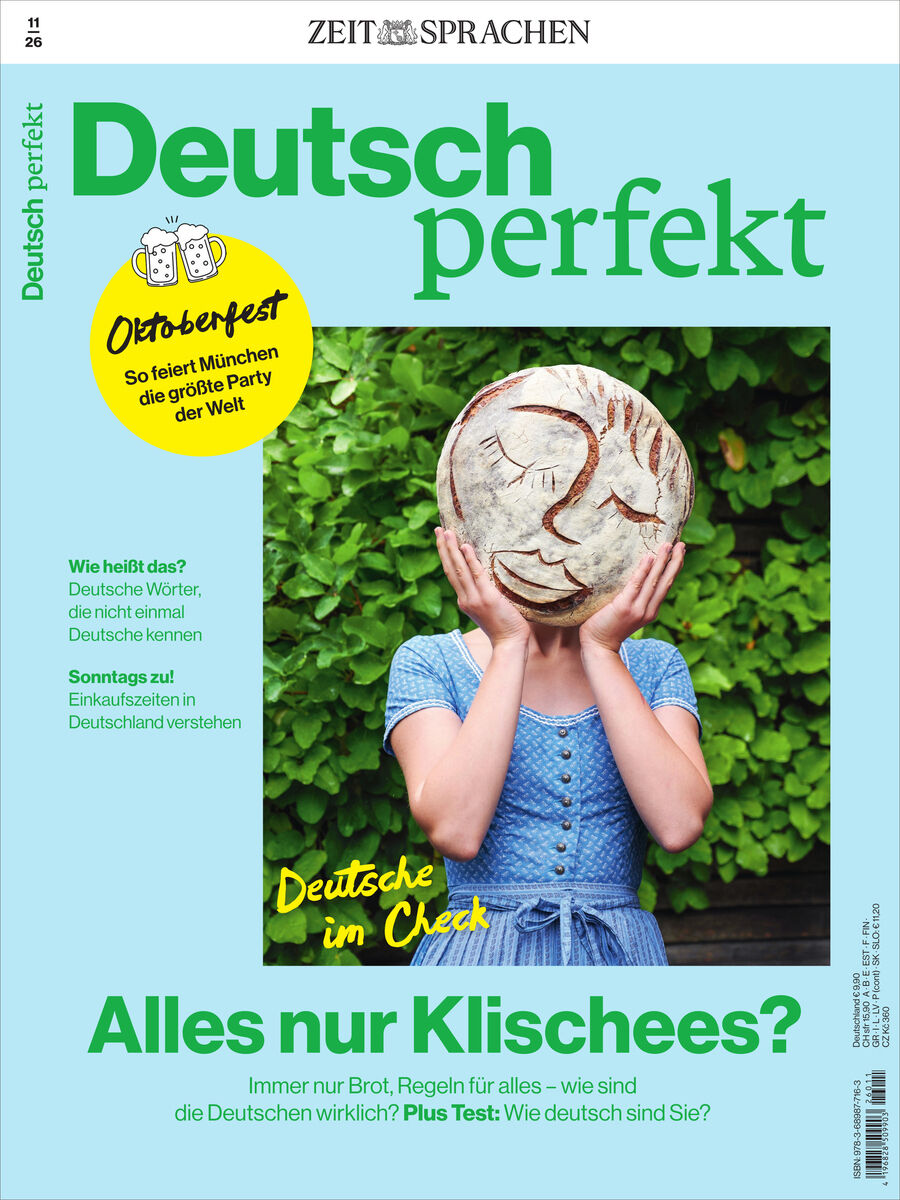 Titelbild des Magazins 'Deutsch perfekt' 11/2026 von Spotlight Verlag. Ein Mensch hält sich ein großes Brot mit lachendem Gesicht vor das Gesicht, steht vor grüner Hecke, trägt blaues Kleid. Slogan: 'Alles nur Klischees?' Thema Oktoberfest und deutsche Kultur.