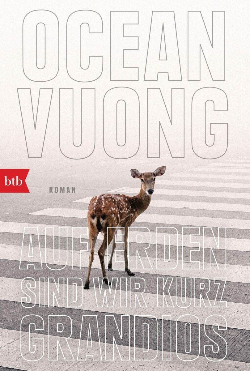 Buchcover des Romans 'Außer Erden sind wir kurz grandios' von Ocean Vuong. Das Cover zeigt ein Reh, das auf einem sonnengebleichten Zebrastreifen steht. Im Hintergrund sind große, helle Buchstaben und ein kleiner roter btb Verlag-Logo zu sehen.