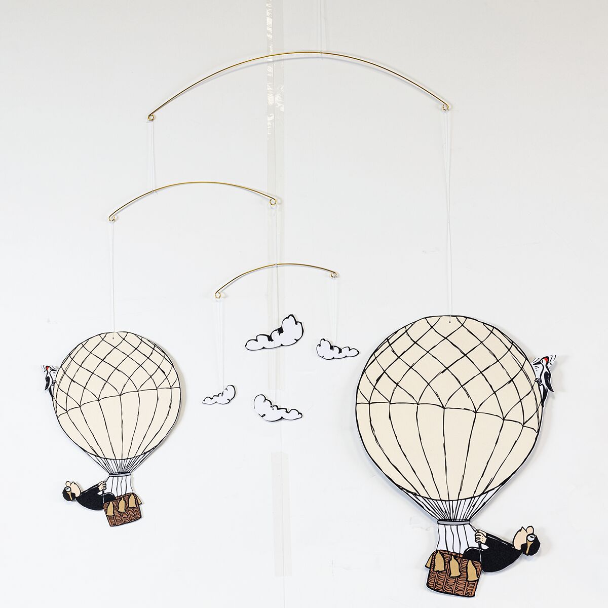 Ein detailreiches Decken-Mobilé von Loriot mit zwei Heißluftballons, jeweils mit Zeichentrick-Figuren im Korb. Drei stilisierte Wolken hängen zwischen den Ballons. Die Motive sind coloriert, die Aufhängung besteht aus feinen goldfarbenen Drahtbögen.