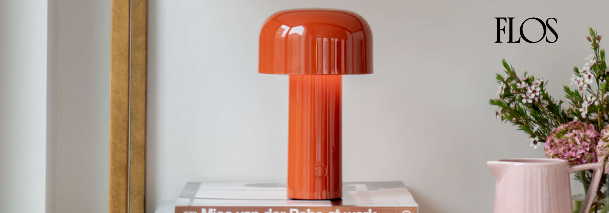 Rote Tischlampe von FLOS mit rundem Lampenschirm auf weißem Tisch neben Vase mit Blumen