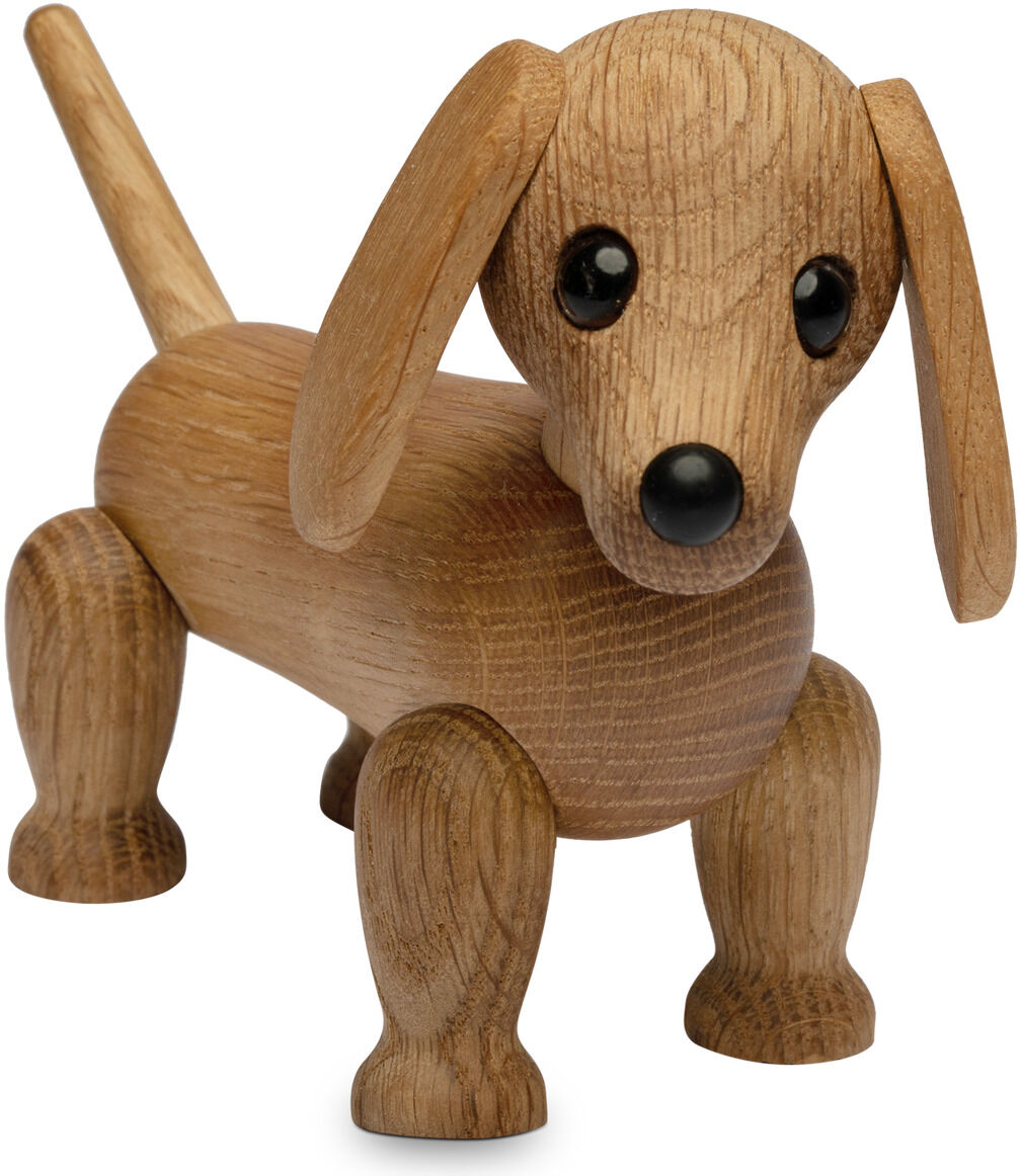 Die Abbildung zeigt eine detailreich gearbeitete Holzfigur eines Dackels namens „Amigo“ von Spring Copenhagen. Die Figur ist aus braunem Holz gefertigt, steht aufrecht, hat schwarze Augen, einen kleinen schwarzen Schnauzenbereich und lange Schlappohren.